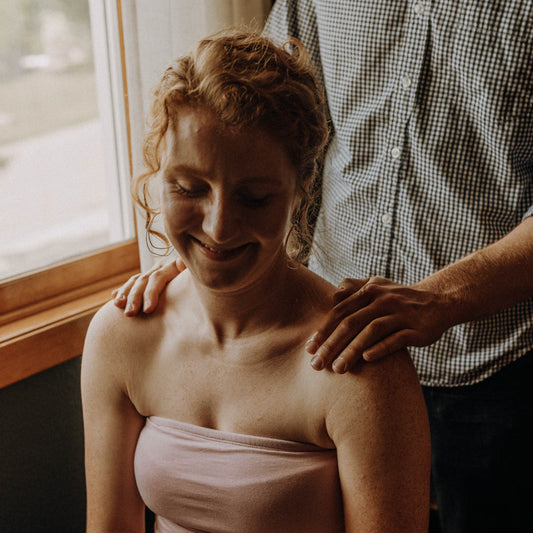 A young woman smiles as she gets her shoulders massaged byher partner.